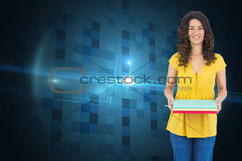 Composite image of smiling curly haired brunette holding notebooks