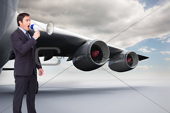 Composite image of standing businessman shouting through a megaphone