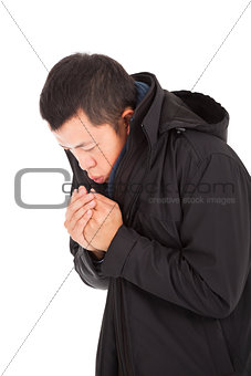 young man blowing to warm hands in cold day