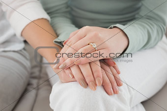 Close-up mid section of female friends touching hands