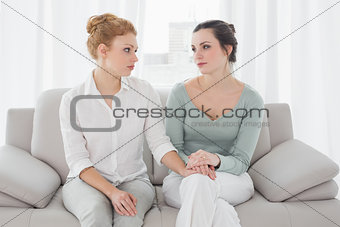 Woman consoling female friend while sitting on sofa