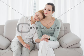 Young woman consoling female friend on sofa