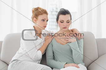 Young woman consoling female friend at home