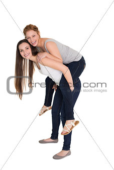 Full length portrait of a young female piggybacking friend
