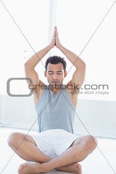 Young man meditating with eyes closed and joined hands