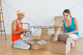 Happy friends unwrapping boxes in a new house