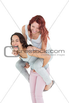 Cheerful young female piggybacking happy friend