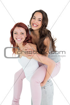 Happy young female piggybacking cheerful friend