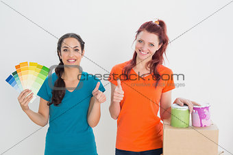 Friends gesturing thumbs up with swatches, box and paint cans