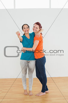 Woman embracing her friend with keys in a new house