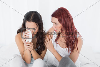 Woman consoling a crying female friend at home