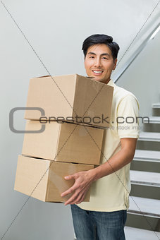 Portrait of a smiling young man carrying boxes