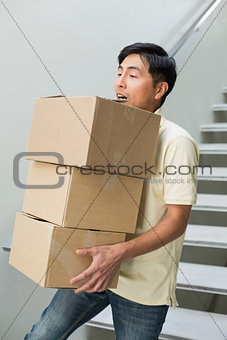 Young man carrying boxes against staircase