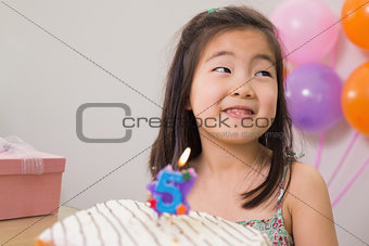 Cute little girl with cake at her birthday party