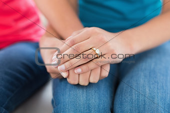Mid section of female friends holding hands at home