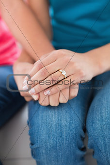 Close-up mid section of female friends holding hands