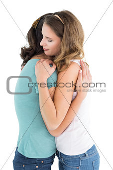 Side view of a young female embracing her friend