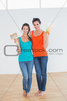 Friends holding paint brush and color swatches in a new house