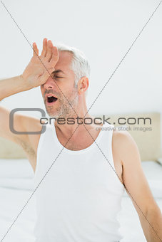 Close-up of a mature man yawning in bed