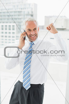 Cheerful businessman using mobile phone in office