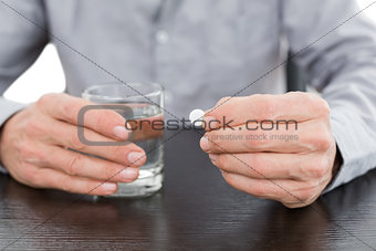 Mid section of a man holding glass of water and pill
