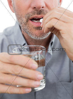 Mid section of a man with glass of water and pill