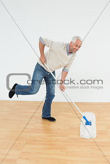 Portrait of a cheerful mature man mopping the floor