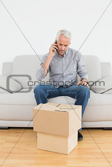 Man using cellpone on sofa with boxes in house