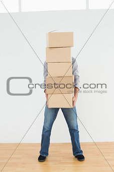 Obscured man carrying boxes in house