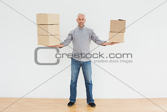 Serious mature man carrying boxes in a new house