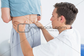 Hands massaging mans lower back in gym hospital