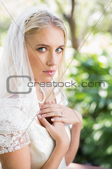 Blonde bride in a veil holding her hands to her chest