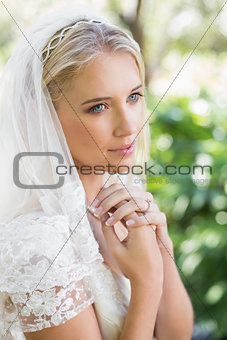 Smiling bride in a veil holding her hands to her chest