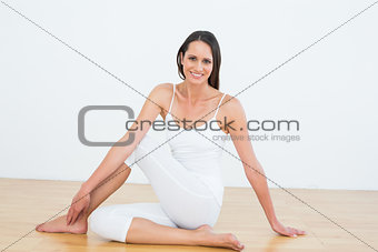 Fit woman doing the half spinal twist pose in fitness studio