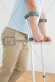 Side view mid section of a man with crutches