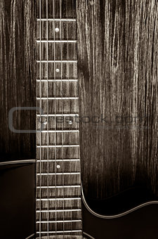 Detail of acoustic guitar in vintage style on wood background