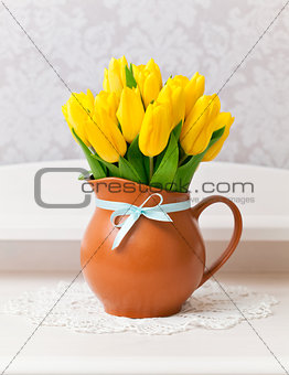 yellow tulips in vase with blue bow