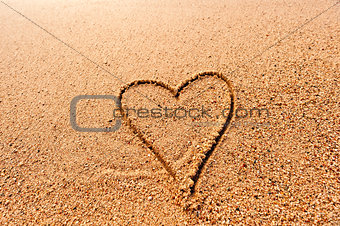 drawing a heart on the wet sand at the sea