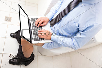businessman  working  in toilet with laptop 