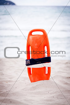 orange red life buoy in sand on beach at the sea object