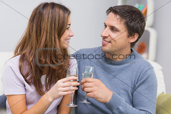 Romantic smiling young couple toasting flutes at home