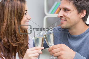 Close-up of a smiling young couple toasting flutes