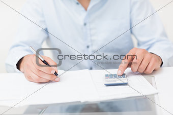 Mid section of a young man with bills and calculator