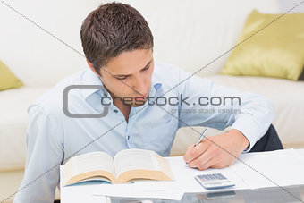 Man with bills and calculator in living room