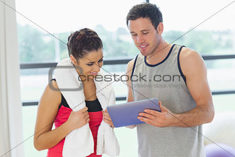 Fit couple looking at digital table in exercise room