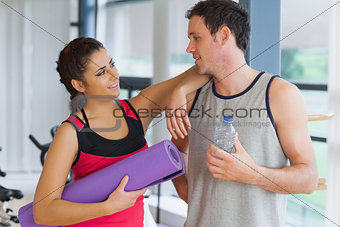 Fit couple with water bottle and exercise mat in exercise room