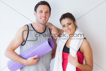 Portrait of a fit young couple with towel and exercise mat