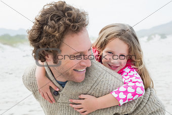 Man piggybacking his daughter at beach