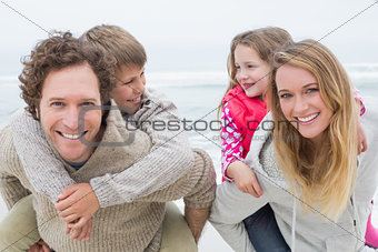 Happy couple piggybacking kids at beach