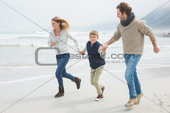 Happy family of three running at beach